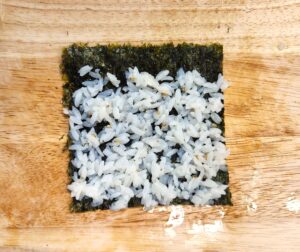 spreading seasoned rice on seaweed sheet for mini kimbap rolling