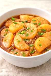 Korean braised radish mu jorim in a bowl with soy glaze and sesame seeds