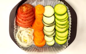 Sliced vegetables layered in a microwave-safe silicone container ready for steaming